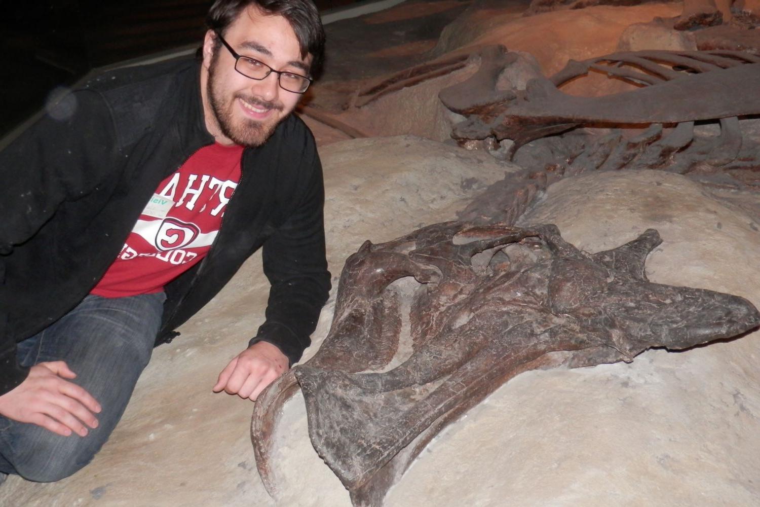 Stephen Hobe '15 poses next to a duck-billed dinosaur skeleton at the Field Museum, the species that was the basis of his senior thesis.